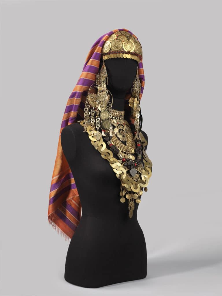 כיסוי ראש סגול וכתום עם הרבה תכשיטי זהב על בובת מניקין