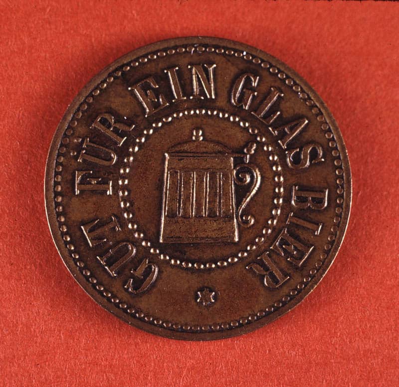 מטבע מנחושת עם תבליט כוס בירה, מונח על רקע אדום