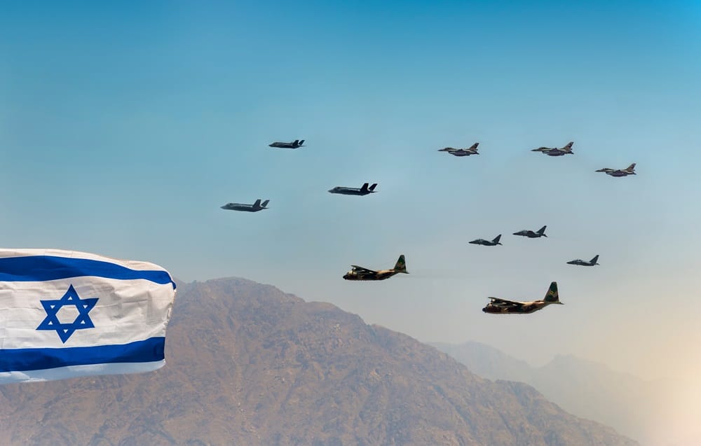 כעשרה מטוסים במטס יום העצמאות טסים מעל הר, ודגל ישראל בצד