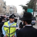 אדם חרדי מול שוטר עם וסט זוהר, ברחוב חרדי