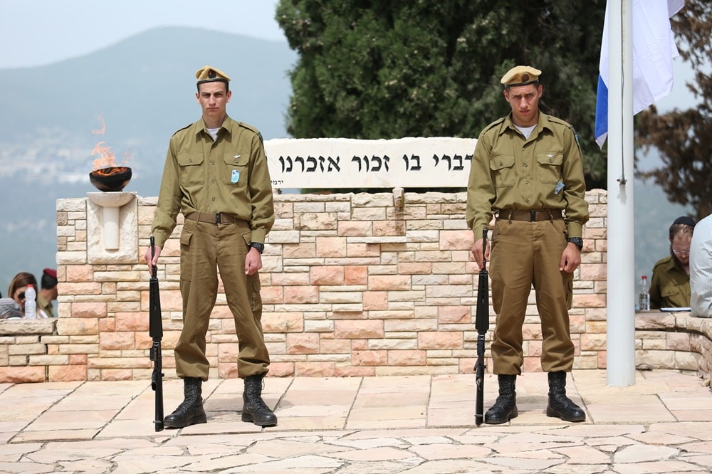 זוג חיילים במשמר כבוד בבית העלמין בהר הרצל, מאחוריהם השלט 'כי מדי דברי בו, זכור אזכרנו עוד'