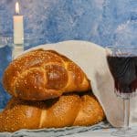 נרות שבת דלוקים, חלות שבת מכוסות וגביע יין לקידוש