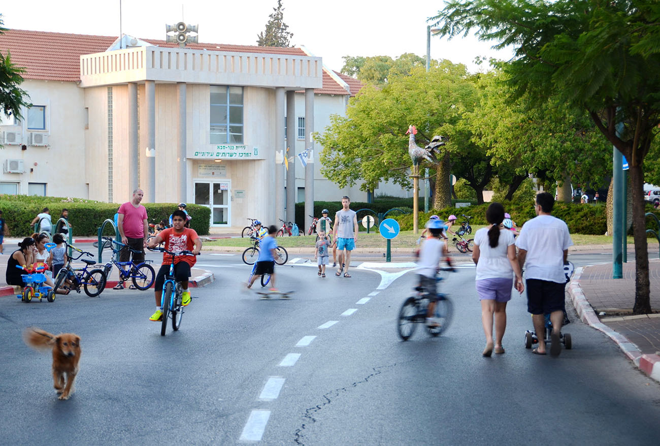 ישראלים רוכבים על אופניים וצועדים על הכביש