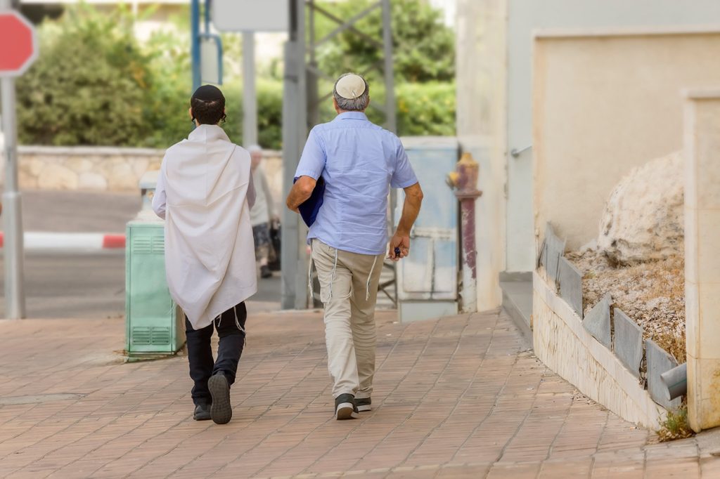 זוג מתפללים מצולמים מאחור צועדים ברחוב