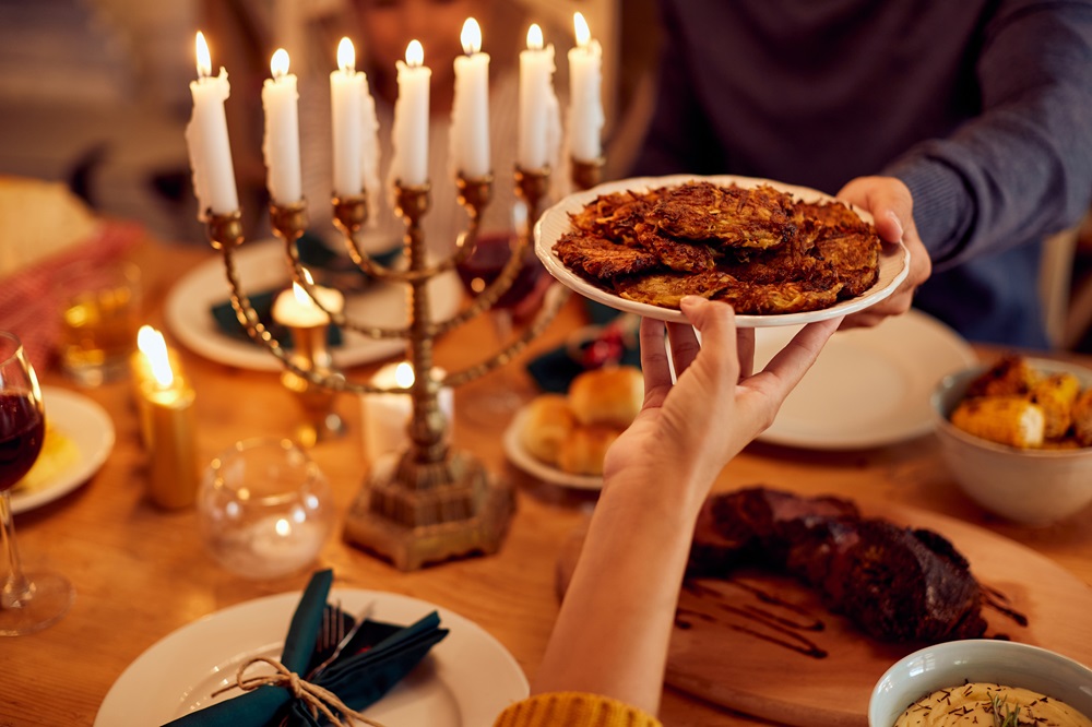 חנוכיה על שולחן חג ויד מעבירה צלחת לביבות