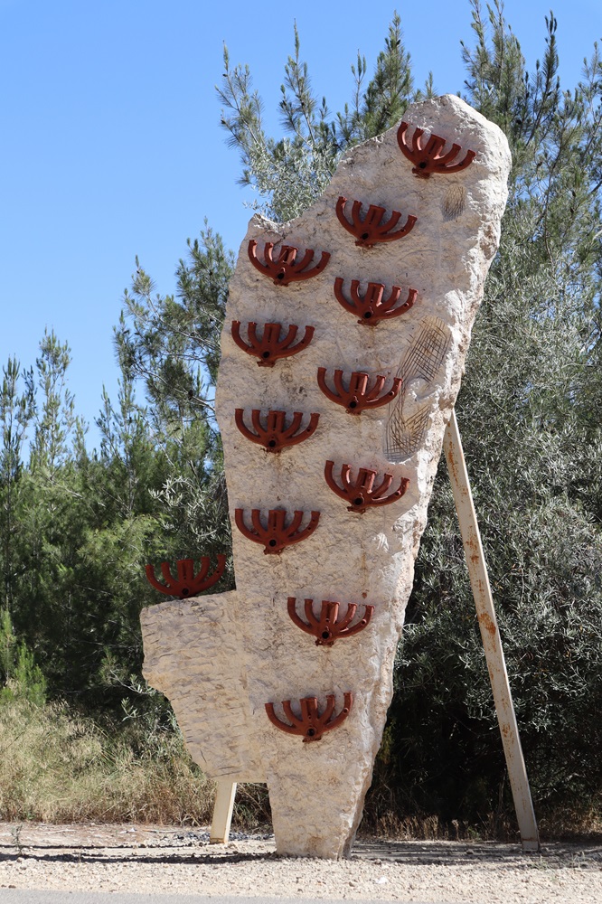 פסל אבן גבוה בצורת ארץ ישראל עם חנוכיות